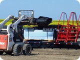 While crew members are measuring containment placement, the Bobcat operator begins to 
unload wall package.